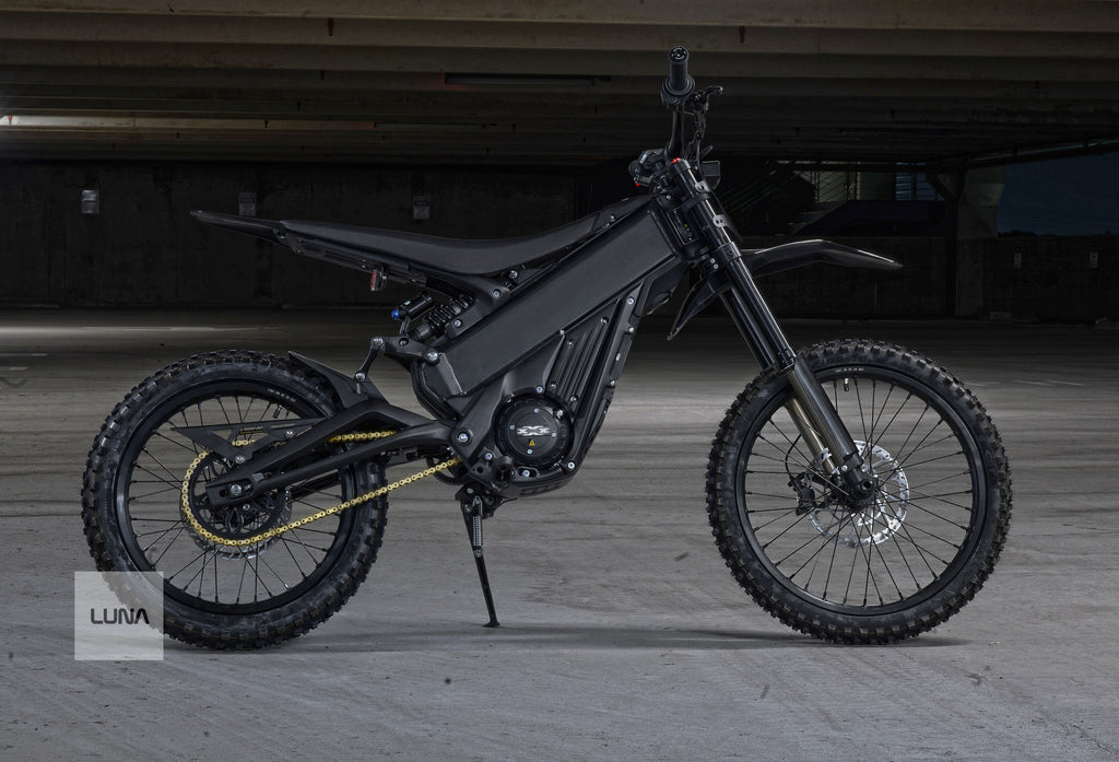 Black electric dirt bike on a concrete surface with 'LUNA' branding.