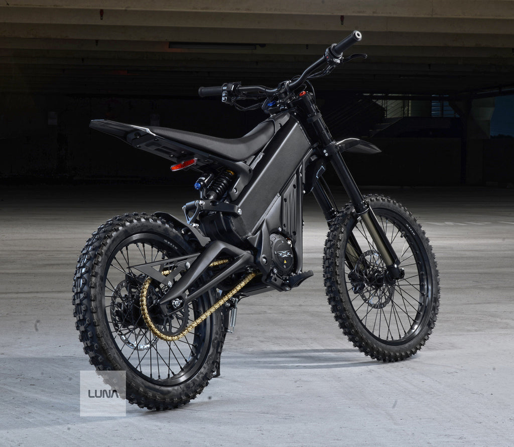 Black electric dirt bike on a wooden floor with a dark background